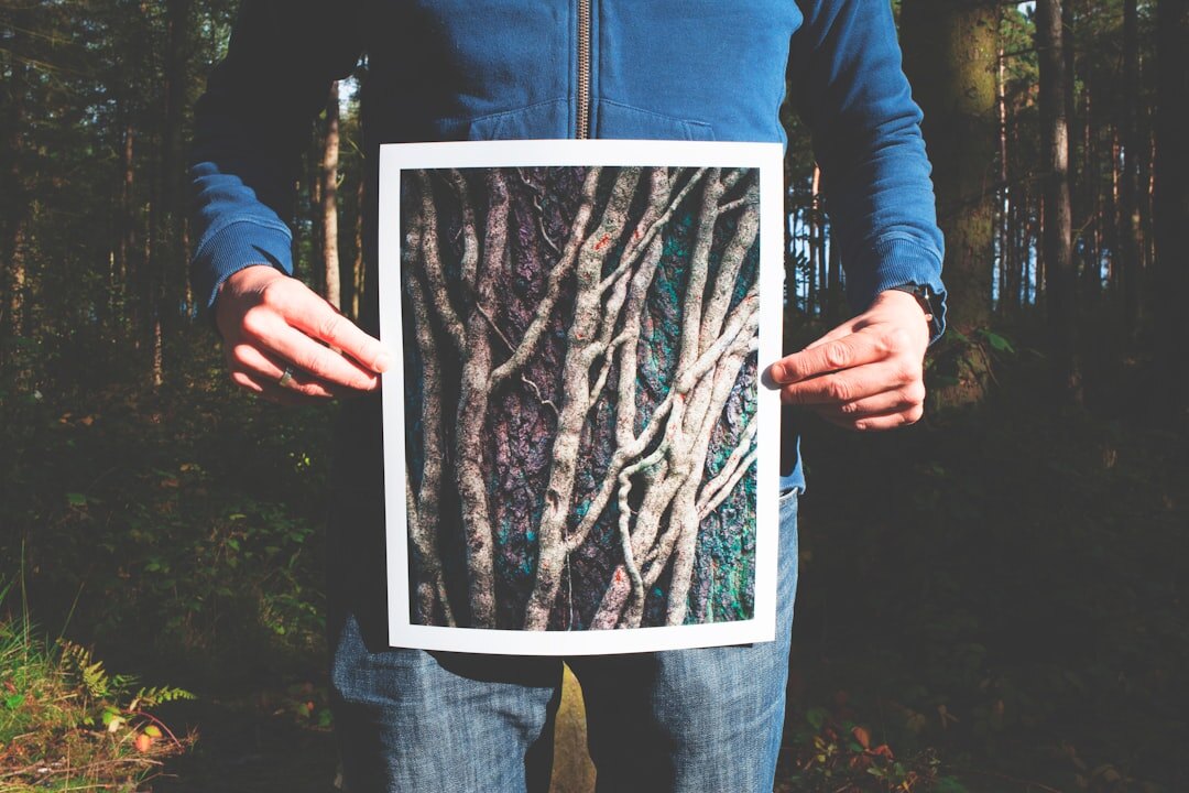 Hands holding a printed black and white photograph outdoors